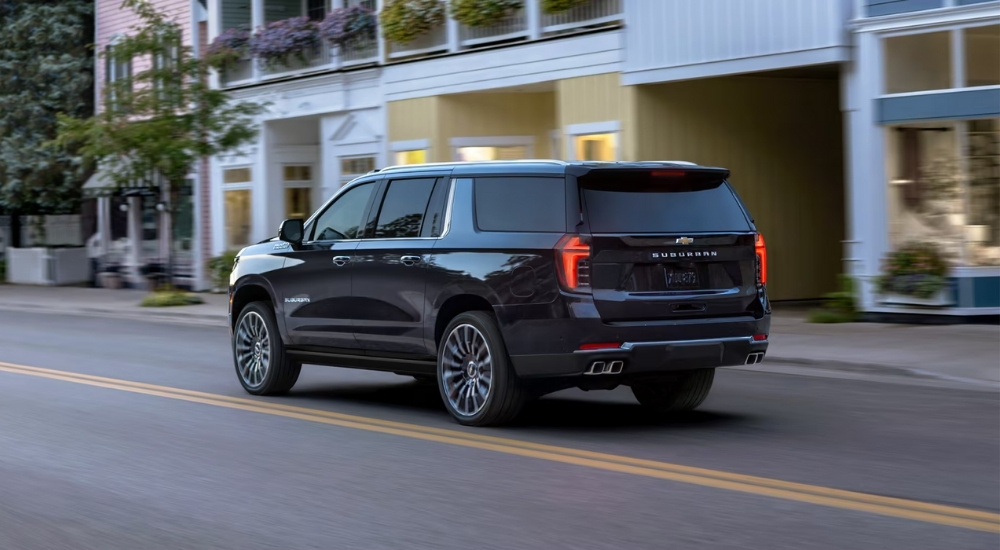 A black 2025 Chevy Suburban driving on a city street.