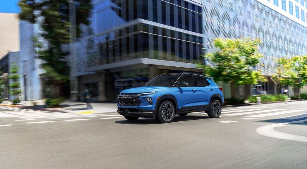 A blue 2024 Chevy Trailblazer RS driving through a city after viewing Chevy SUVs for sale.
