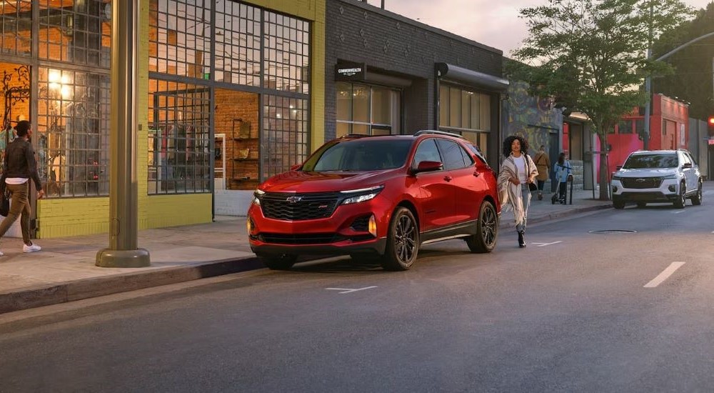 A woman is walking towards a red 2024 Chevy Equinox RS for sale.