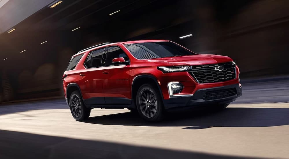 A red 2023 Chevy Traverse RS for sale is shown driving through a tunnel.