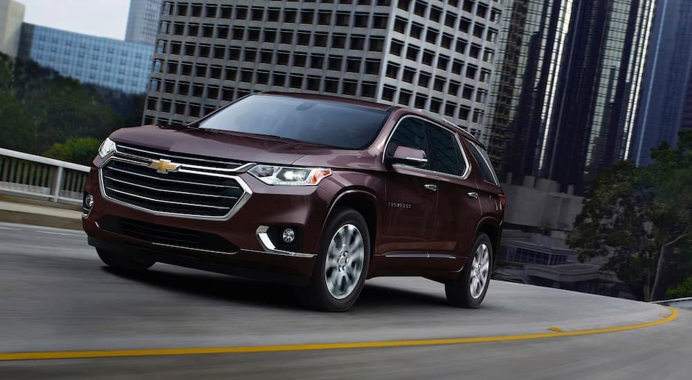 A maroon 2020 Chevy Traverse is shown driving on a highway after leaving a used Chevy dealership.