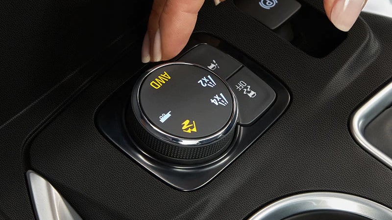 A hand pressing the button on a car's air conditioning system, adjusting the temperature settings.