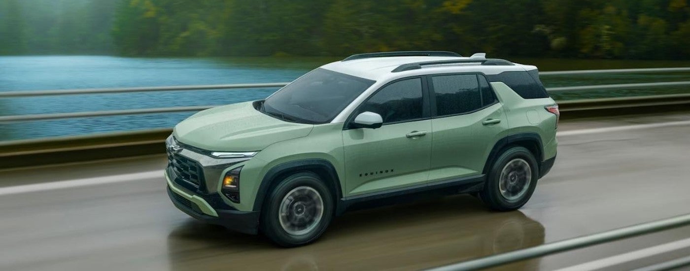 A green 2025 Chevy Equinox ACTIV is shown driving on a bridge.