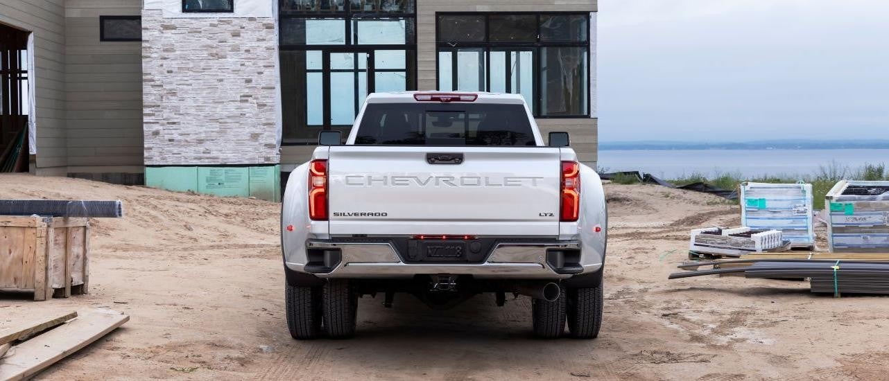 A white 2024 Chevy Silverado 3500HD LTZ is shown from the rear at a construction site.