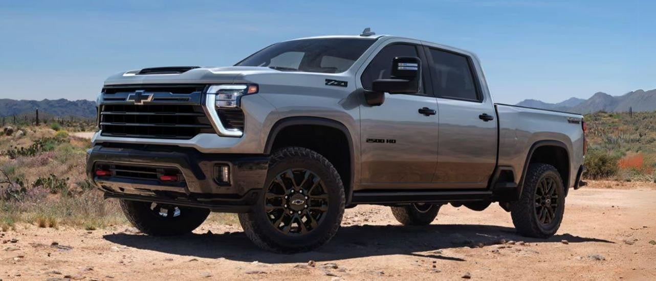 A grey 2024 Chevy Silverado 2500HD TrailBoss is shown from the side parked off-road.